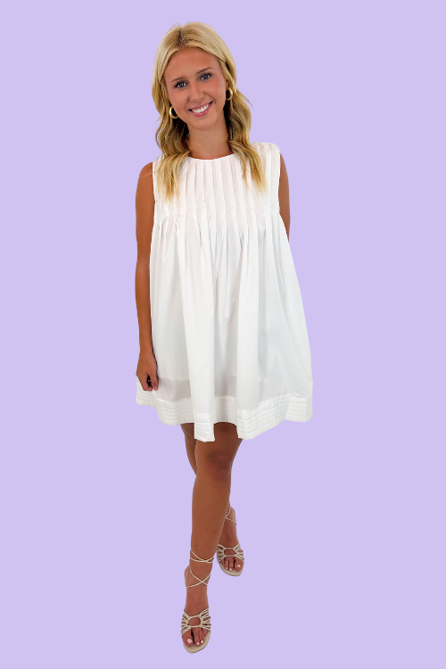 White in color Sleeveless mini dress Round neckline Pleated detailing&nbsp; Side Pockets Zipper at back Relaxed fit throughout bodice 80% Polyester, 20% Cotton
