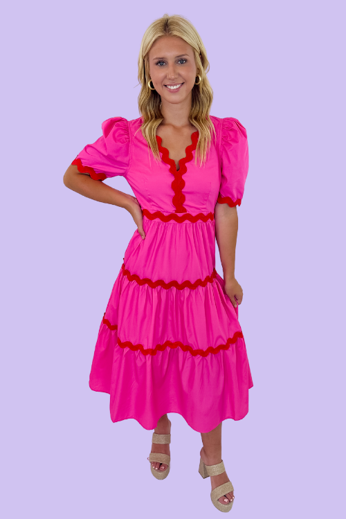 Pink in color Midi Dress Red Ric Rac on trim V-neckline Puff sleeves Tiered Bodice Zipper closure at back Lined, non-sheer 65% Polyester, 35% Cotton Model is wearing a size small