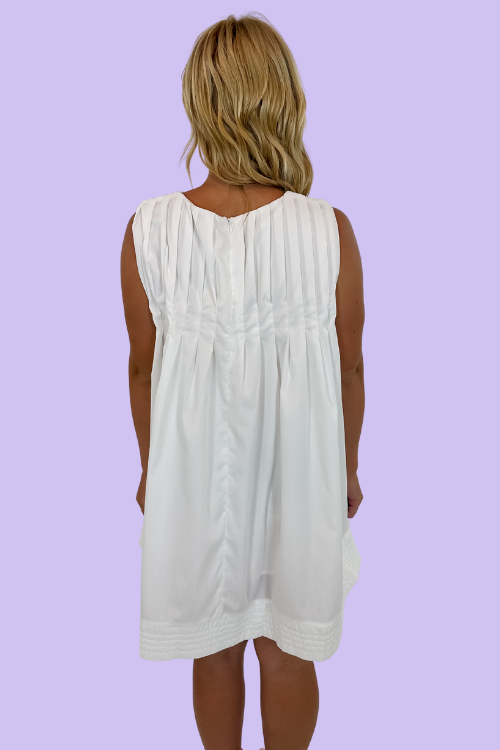 White in color Sleeveless mini dress Round neckline Pleated detailing&nbsp; Side Pockets Zipper at back Relaxed fit throughout bodice 80% Polyester, 20% Cotton